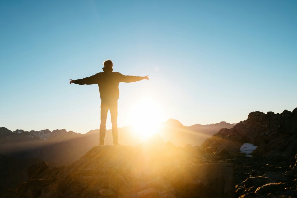 person standing on hill silhouetted by the sun