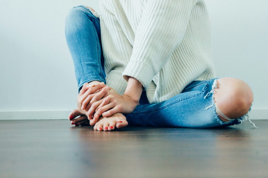 person sitting on the floow holding their ankle