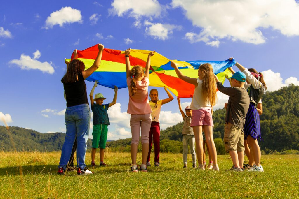 group of children playing with a rainbow tarp