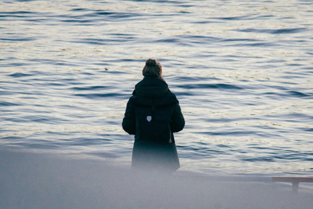 person standing in cold weather looking at the ocean