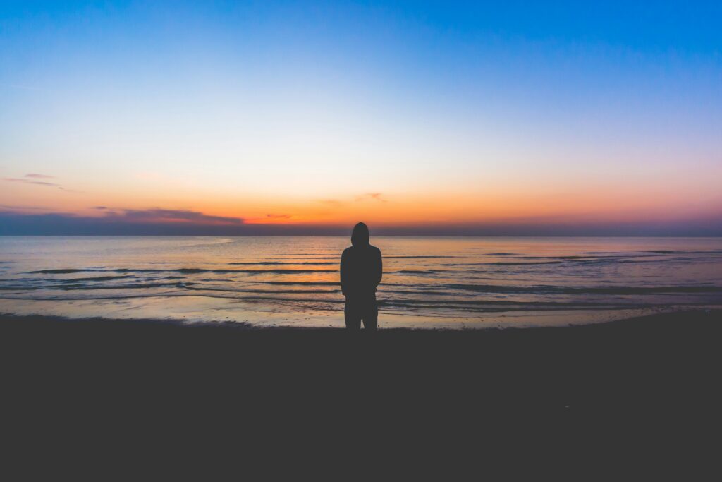 person standing alone on a post-sunset beach