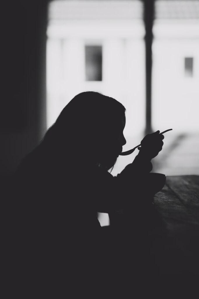 Woman silhouetted eating soup with a spoon